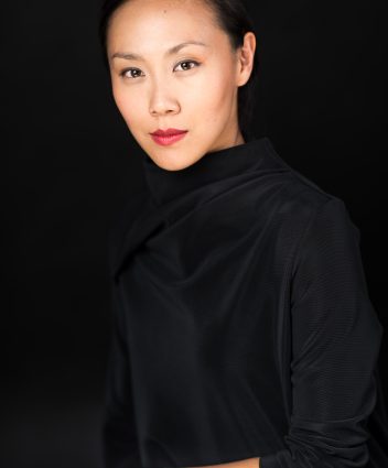 Jasmine Chen, seated looking straight ahead, wearing black with a black background