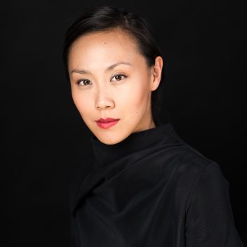 Jasmine Chen, seated looking straight ahead, wearing black with a black background