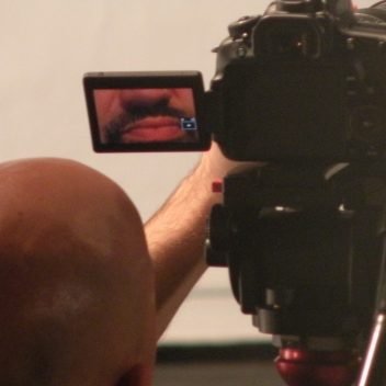 Close up of a camera, the screen of the camera has someone’s mouth in focus on it