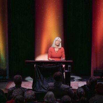 Jane at the piano singing to an audience.